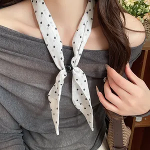 Detalle de un pañuelo de algodón y lino con lunares usado como accesorio de collar