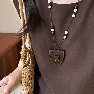 Close-up of a stylish brown beaded necklace with a polka dot pendant worn by a model