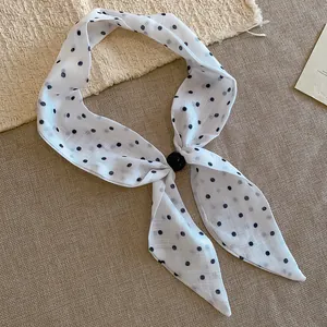 Vista detallada de un pañuelo vintage blanco con lunares negros y cuenta decorativa
