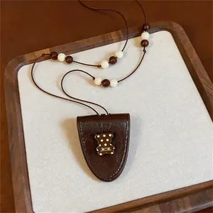 Close-up of brown leather bear pendant necklace with white polka dots and beaded string.