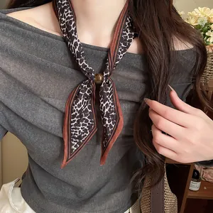 Detalle de pañuelo vintage de algodón con estampado de leopardo y una cuenta decorativa.