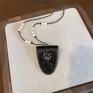Detailed view of a stylish black cat pendant necklace with pearls and polka dot patterns.