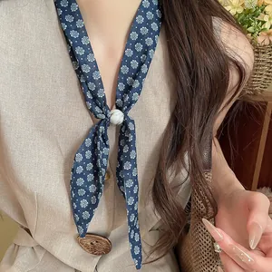 Detalle de una bufanda de algodón con flores retro y un elegante anillo decorativo