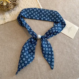 Detalle de un pañuelo vintage de algodón y lino con estampado floral y hebilla blanca