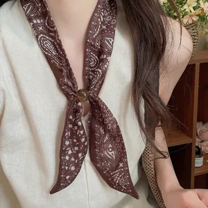 Primer plano de bufanda de lino con estampado paisley vintage y hebilla ámbar