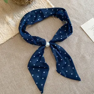 Primer plano de pañuelo vintage de algodón con lunares y detalle de perla.