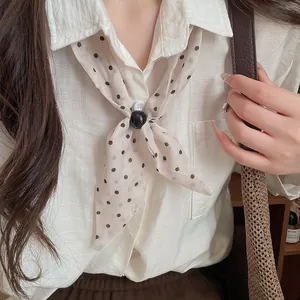 Primer plano de un pañuelo vintage de lunares anudado en una camisa blanca de lino chic