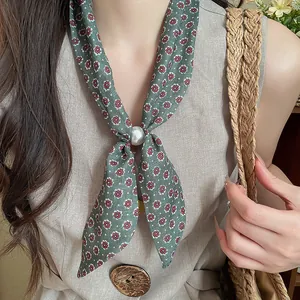 Primer plano de un pañuelo vintage de algodón y lino con flores y perla en una modelo