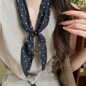 Detalle de bufanda vintage de algodón y lino con lunares y una elegante hebilla de anillo.