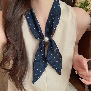 Primer plano de un pañuelo vintage de algodón y lino a lunares con un elegante detalle de perla