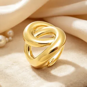 Gros plan d'une bague torsadée en acier inoxydable plaqué or 18K sur un tissu doux.