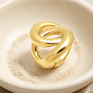 Gros plan d'une bague en acier inoxydable plaqué or 18 carats au design géométrique torsadé.
