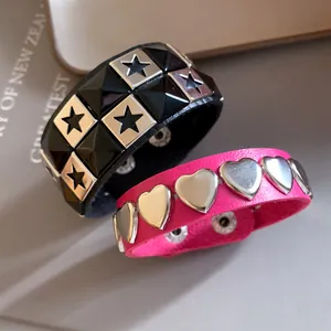 Detail macro view of black star stud and pink heart stud leather punk bracelets.