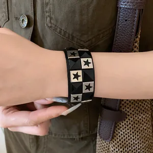 Detailed view of a black leather bracelet featuring silver star studs and pyramid accents.