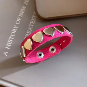 Detail view of pink leather heart-studded bracelet with silver metallic snap buttons.