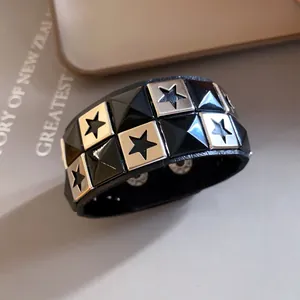 Close-up of a black leather cuff bracelet with silver star studs and black pyramid spikes.