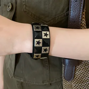 Close-up of a trendy leather bracelet with metal stars and pyramid studs on wrist.