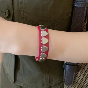 Detailed view of fashionable pink leather bracelet with metal heart studs worn on wrist