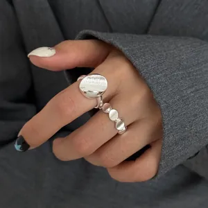 Detail view of minimalist matte silver circular open ring and multi-disc band on hand