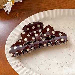 Vintage brown acrylic hair claw clip with cream polka dots and a stylish bow design.