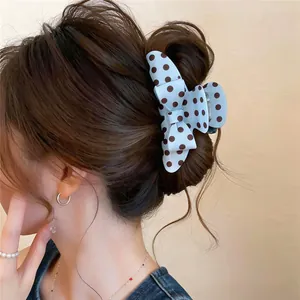 Close-up of a blue polka-dot bow claw clip styled in a classic bun hairstyle.