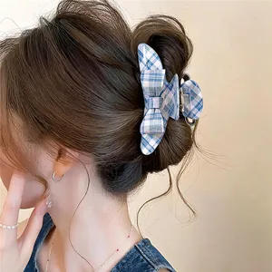 Close-up of a stylish blue plaid acrylic bow hair claw clip used for a hair bun.