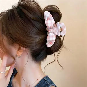 Detail shot of a pink checkered bow hair claw clip styled in a classic hair bun.