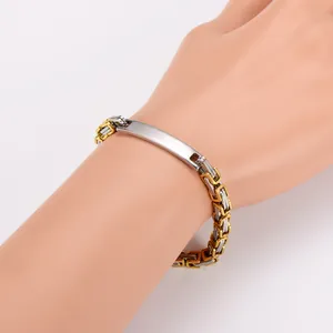 Close-up of a two-tone Byzantine link bracelet with a polished metal ID plate on a wrist