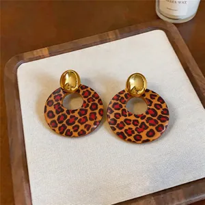 Nahaufnahme der runden Holz-Ohrstecker mit Leopardenmuster und Goldstecker.