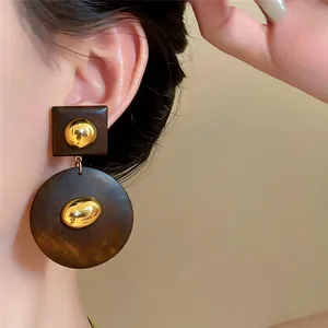 Nahaufnahme von Retro-Holzohrringen mit geometrischen Formen und edlen Goldakzenten