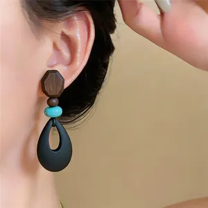 Detailaufnahme eines ethnischen Vintage-Ohrrings aus Holz und Türkis am Ohr getragen