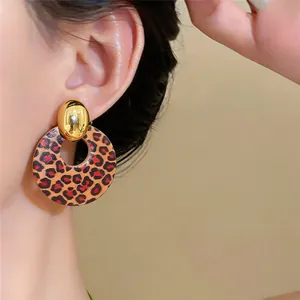 Nahaufnahme von runden Retro-Holzohrsteckern mit Leopardenmuster und Goldstecker