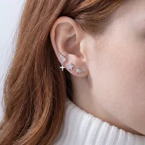 Elegant silver angel wing and sparkling star stud earring set worn on model's ear