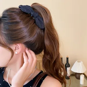 Dettaglio di un fermaglio per capelli vintage a fiocco in tessuto a pois su coda.
