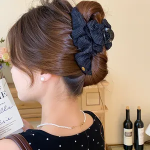 Dettaglio della clip per capelli vintage con fiocco in tessuto a pois neri per chignon
