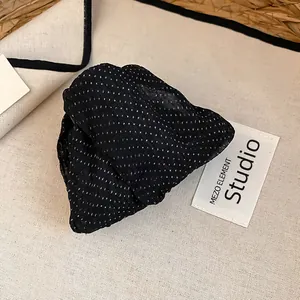 Dettaglio ravvicinato di una molletta per capelli in tessuto a pois neri su tela.