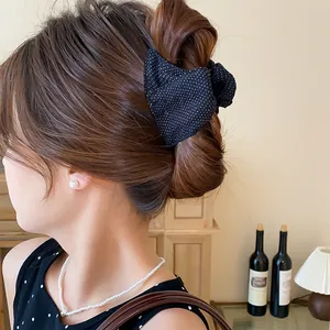 Vista laterale di un fermaglio per capelli vintage con fiocco a pois indossato da una modella.