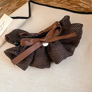 Primo piano del fermaglio per capelli vintage a pois marroni con fiocco in raso lucido