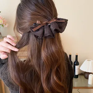 Dettaglio di un fermaglio per capelli a fiocco marrone a pois su una pettinatura