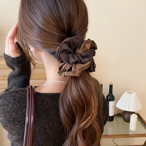 Dettaglio di un grande elastico scrunchie vintage marrone a pois in una coda di cavallo