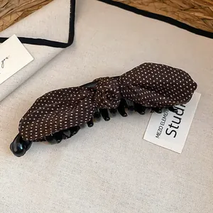 Dettaglio ravvicinato della molletta a banana con fiocco marrone a pois vintage