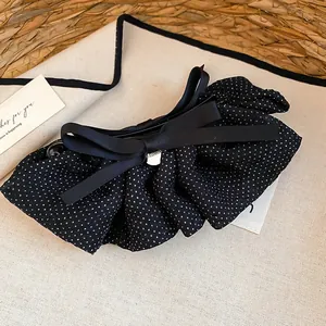 Dettaglio del fermaglio per capelli vintage a pois neri con fiocco in tessuto