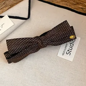 Dettaglio ravvicinato di un fermaglio per capelli vintage a pois marroni con fiocco