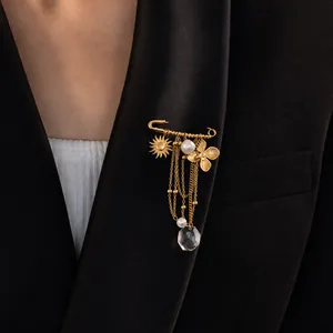 Primo piano di una spilla a balia placcata oro 18K con charms a forma di sole e fiori.