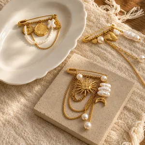 Dettaglio di spille in acciaio inossidabile placcate oro 18K con ciondoli sole e perle.