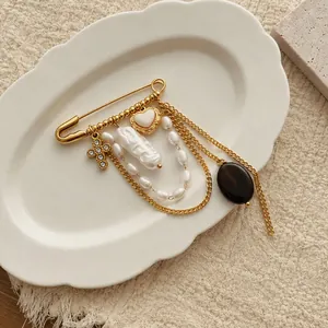 Dettaglio ravvicinato della spilla placcata oro 18K con perle e charms a croce