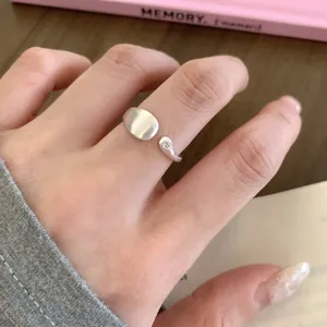 Elegant close-up of a minimalist matte silver open ring featuring a tiny zircon on a finger
