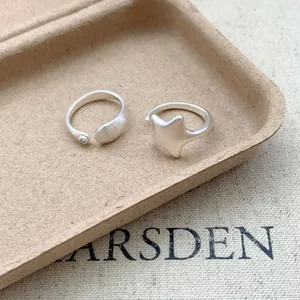 Macro detail of minimalist matte silver open rings with star and zircon motifs on tray