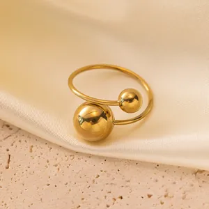 Primo piano di un anello aperto minimalista in acciaio al titanio placcato oro 18K con due sfere