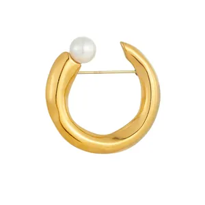 Macro view of gold-plated stainless steel C-shape brooch with elegant pearl detail.